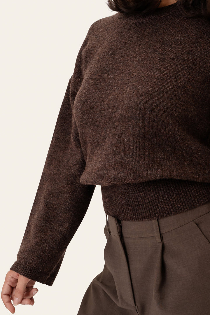 Mørkebrun dame sweater med rund hals, foldet på bord. Blød, langærmet trøje til afslappet og stilfuld brug.