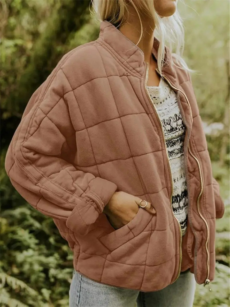 Stilfuld vatteret damejakke, mellemlang, med et moderne blokmønster design.