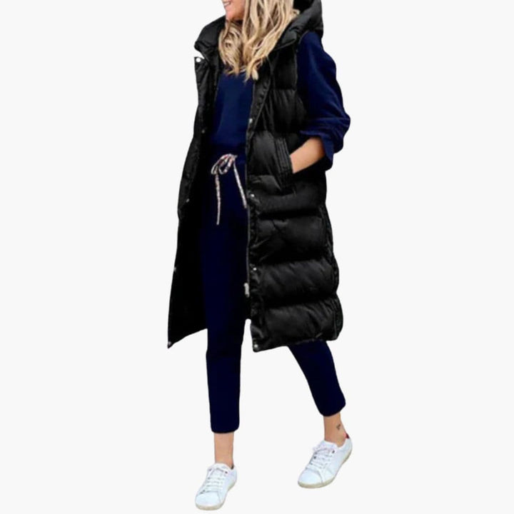 Kvinde bærer lang, sort quiltet gilet med hætte. Stilfuld mode til efterår og vinter.