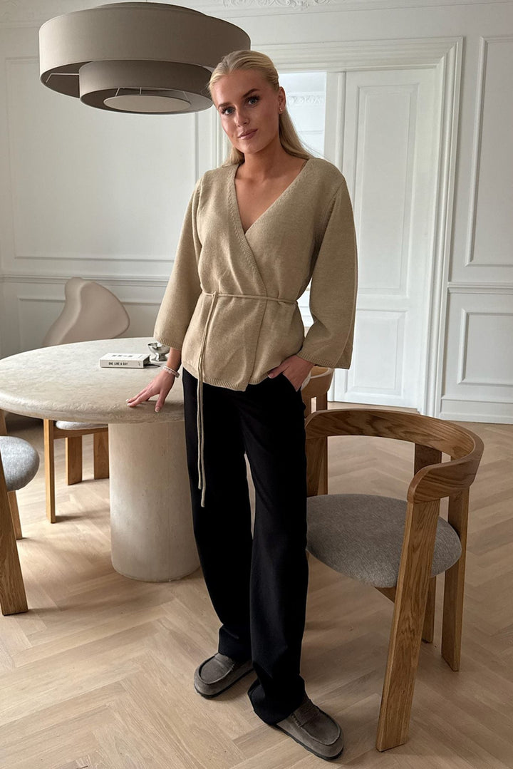 Langærmet beige slå-om cardigan med justerbart bælte. Perfekt til en elegant og afslappet stil.