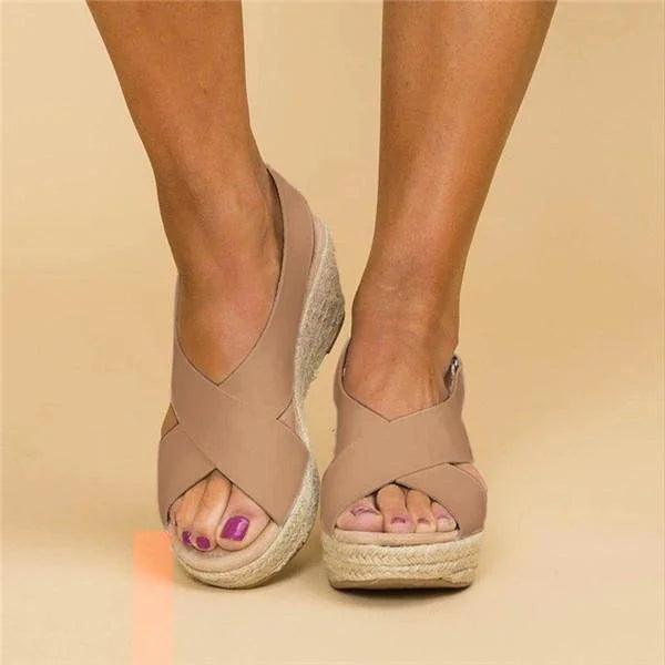 Nærbillede af kvinders ortopædiske sommersandaler med flettet espadrille kilehæl for stil og støtte.