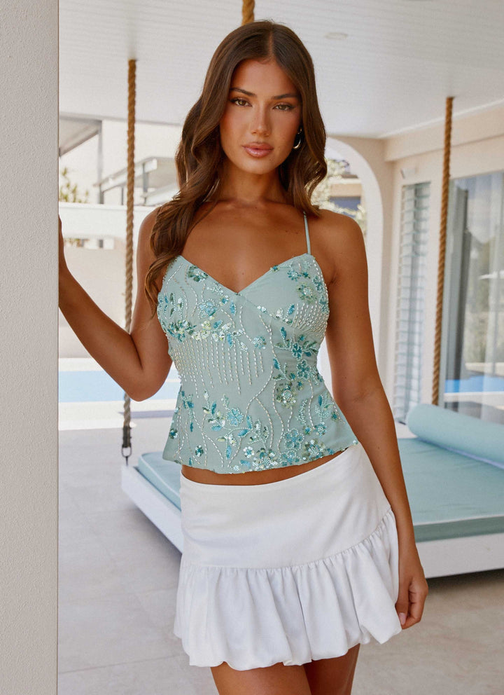 Trendy dame festtop med perler, glimmer og spaghettistropper til moderne aftenlook.