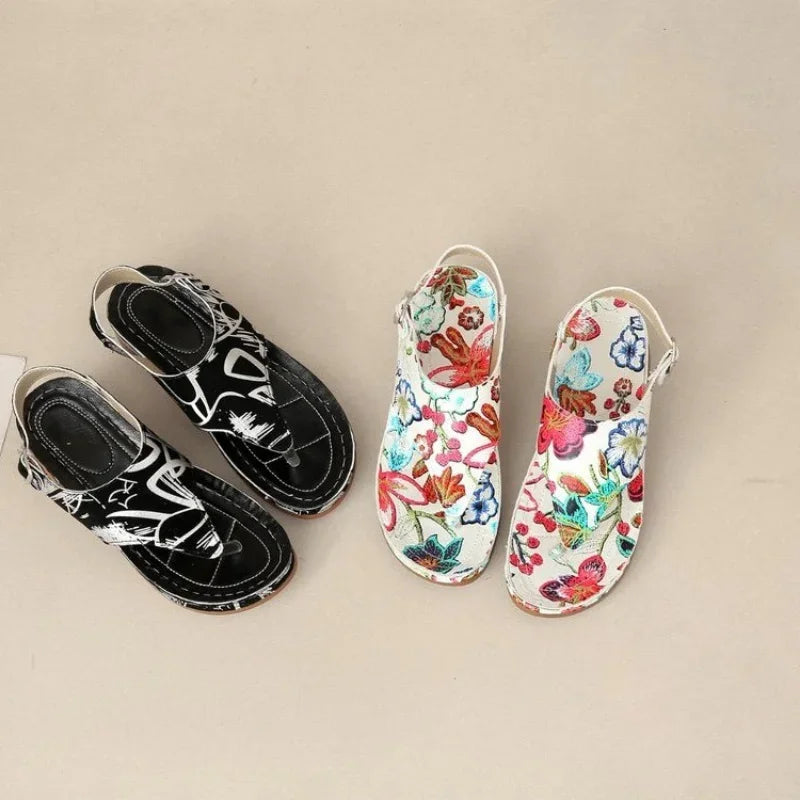 Stilfuld dame sandal med kilehæl. Sort/hvid blomstret design og justerbare stropper for sommerens mode.