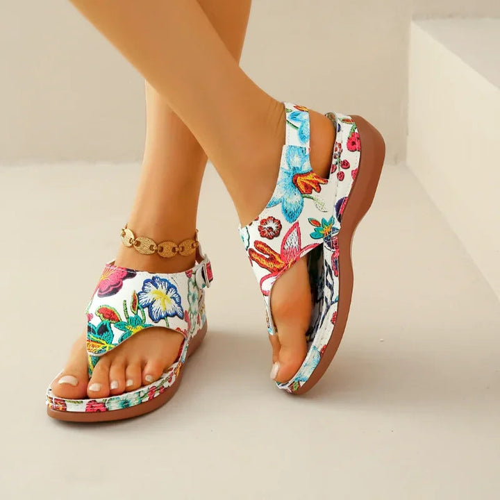 Sommerlig dame sandal med kilehæl og blomsterprint. Ortopædisk komfort og stilfuldt fodtøj til strand og sol.