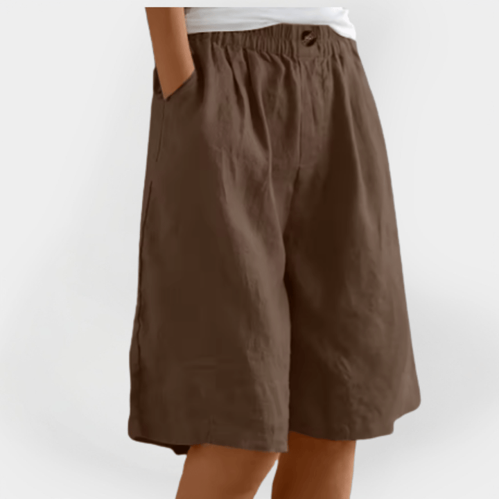 Kvinde iført sorte dameshorts med elastisk talje og løs pasform, perfekt til en afslappet sommerdag.