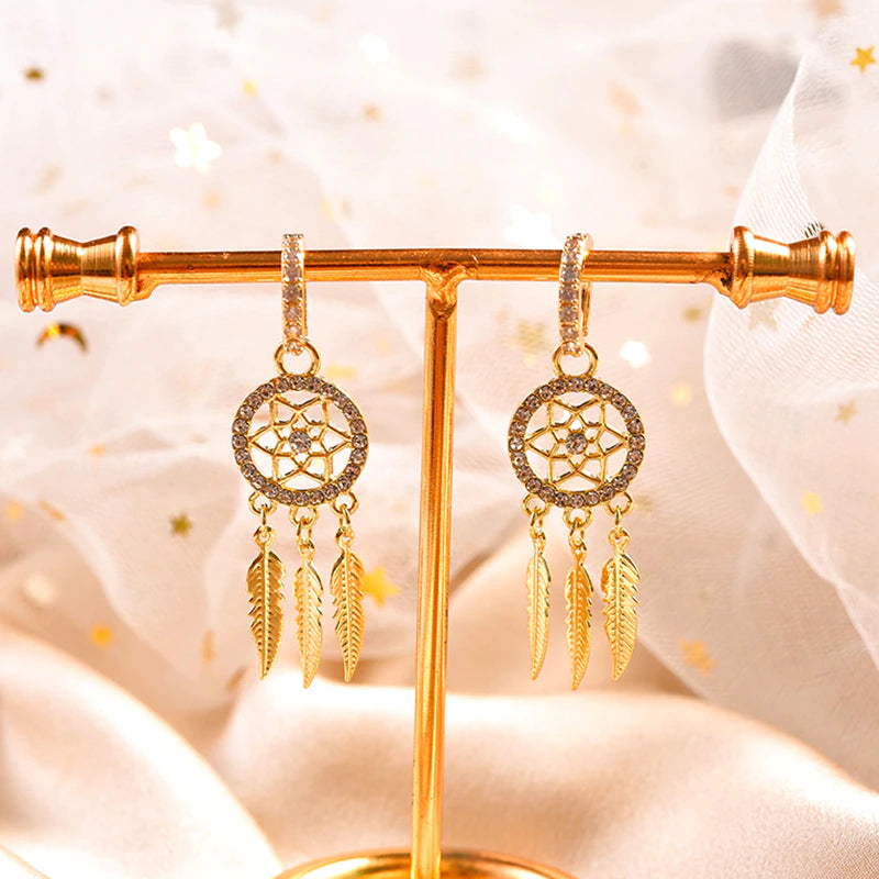 Unikke drømmefangerøreringe i 14 karat guld til kvinder. Elegante smykker med krystaller og fjerdetaljer.