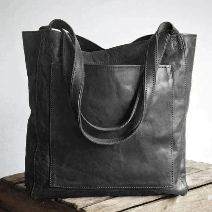 Kvinde med elegant brun læder skuldertaske, den perfekte hverdagstaske som fuldender dit stilfulde look.