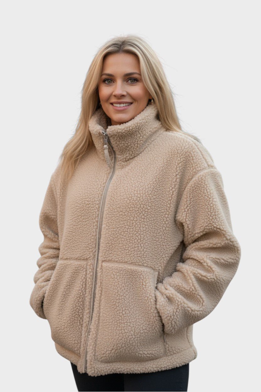 Kvinde iført en moderne og varm cremefarvet teddy-kåbe i nordisk stil. Ideel for komfort og mode.
