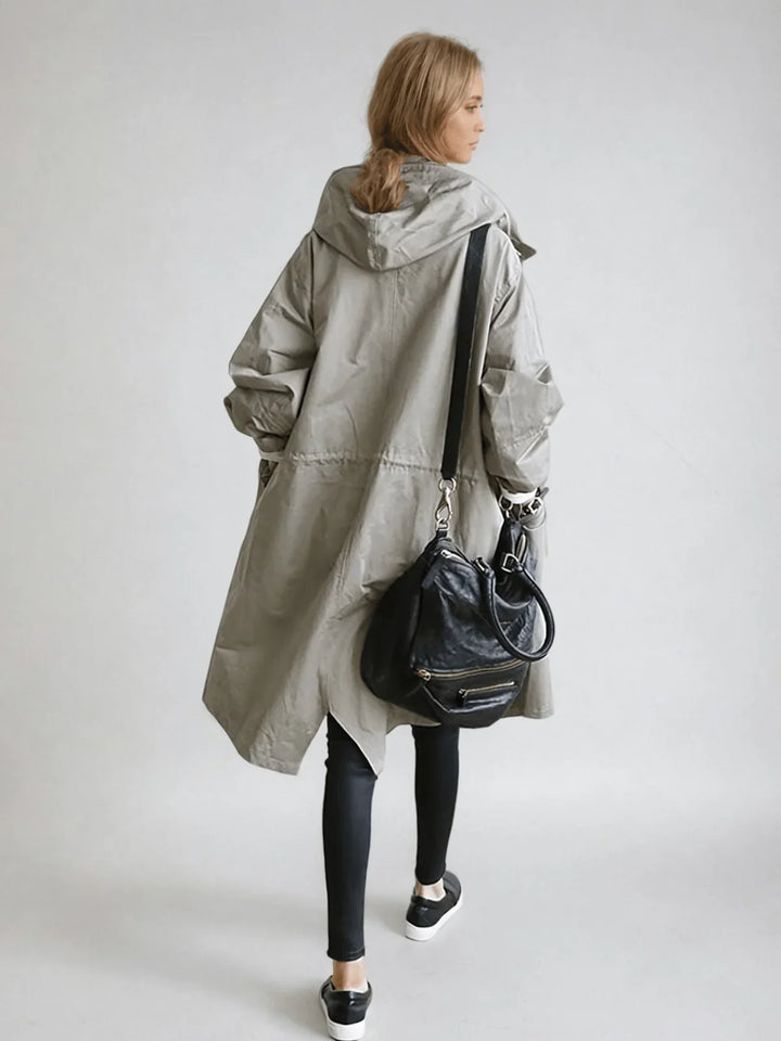 Dame trenchcoat med hætte, set fra siden. Funktionel og trendy regnjakke, perfekt til ustadigt vejr.