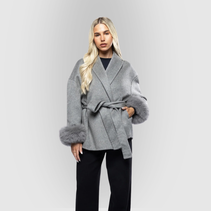 Elegant damejakke med faux fur manchetter og stilrent taljebælte for en feminin pasform.