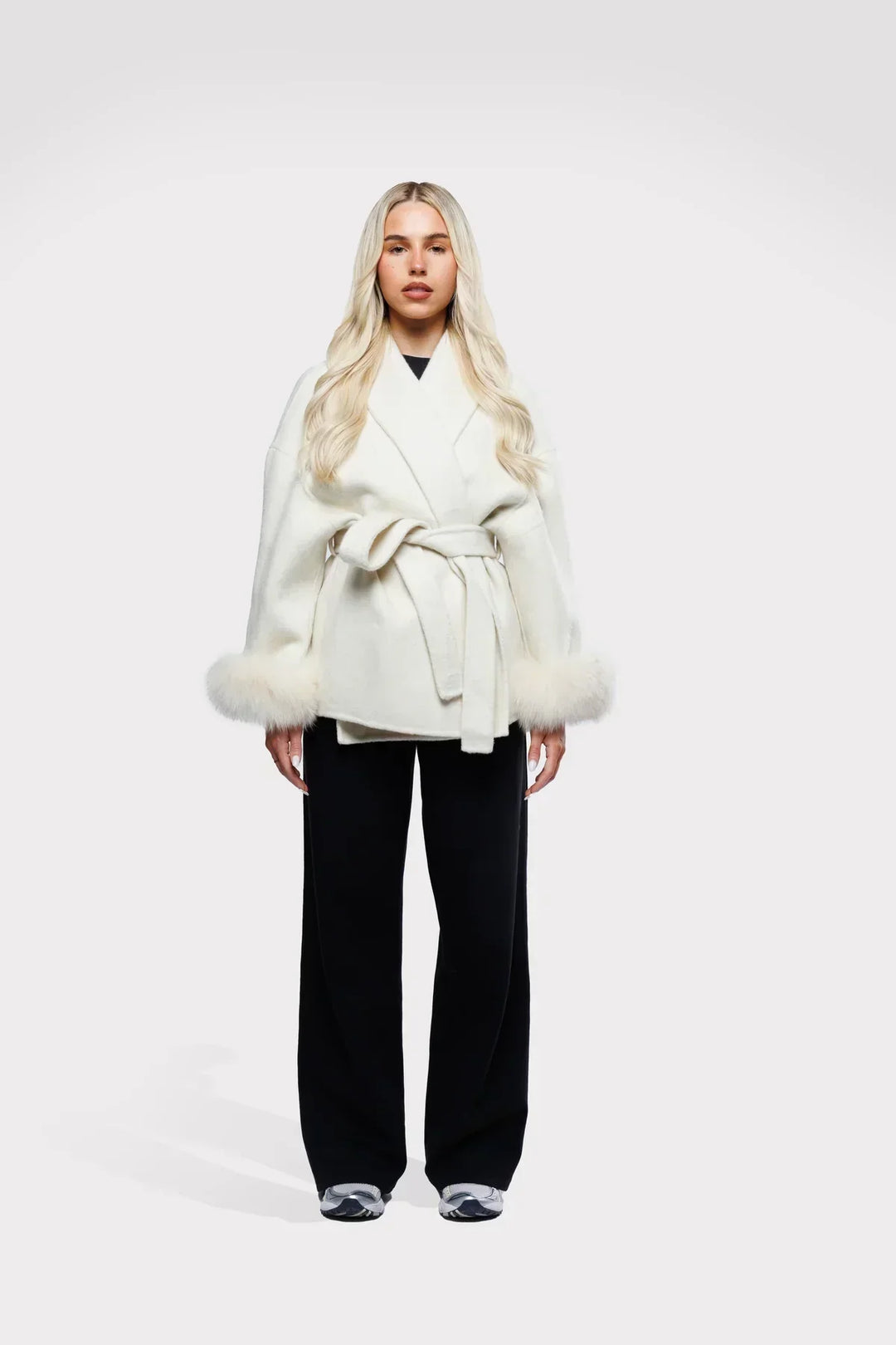 Feminint designet vinterjakke med faux fur manchetter og taljebælte, der giver et elegant look.