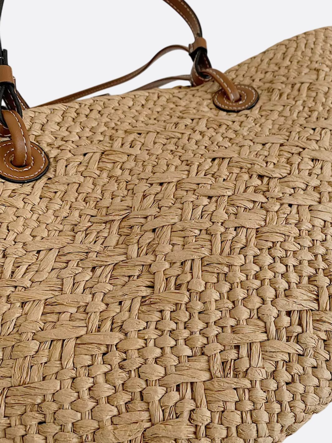 Chic beige stråtaske i tote-stil med brune læderhåndtag. Elegant flettet sommertaske til moderne kvinder.