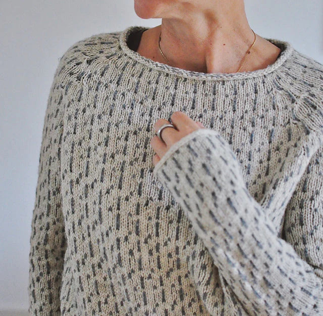 Model iført elegant grå kvinders sweater med bådudskæring. Komfortabel, langærmet overdel til et stilfuldt look.