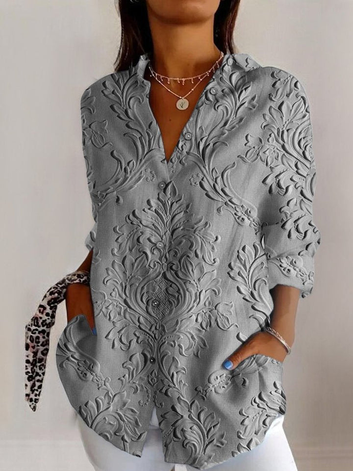 Grå allround damebluse med elegant præget blomsterdesign. Langærmet V-udskæring for en sofistikeret stil.