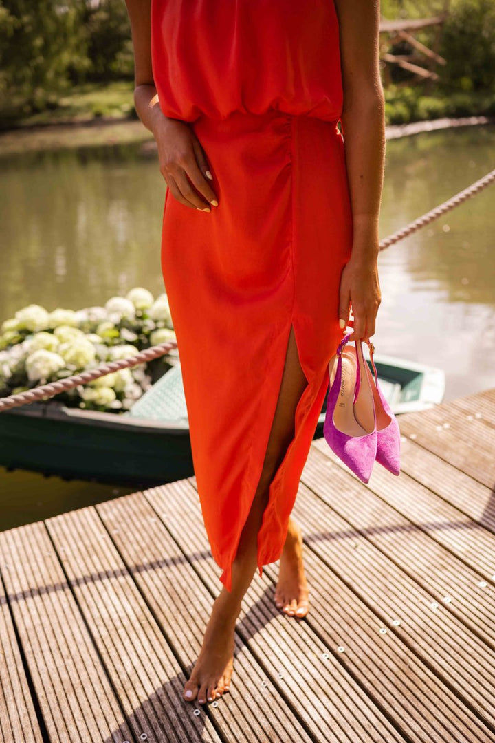 Model iført en smuk gul/orange elegant sommer midi kjole, der bevæger sig let og luftigt. Komfortabel stil.