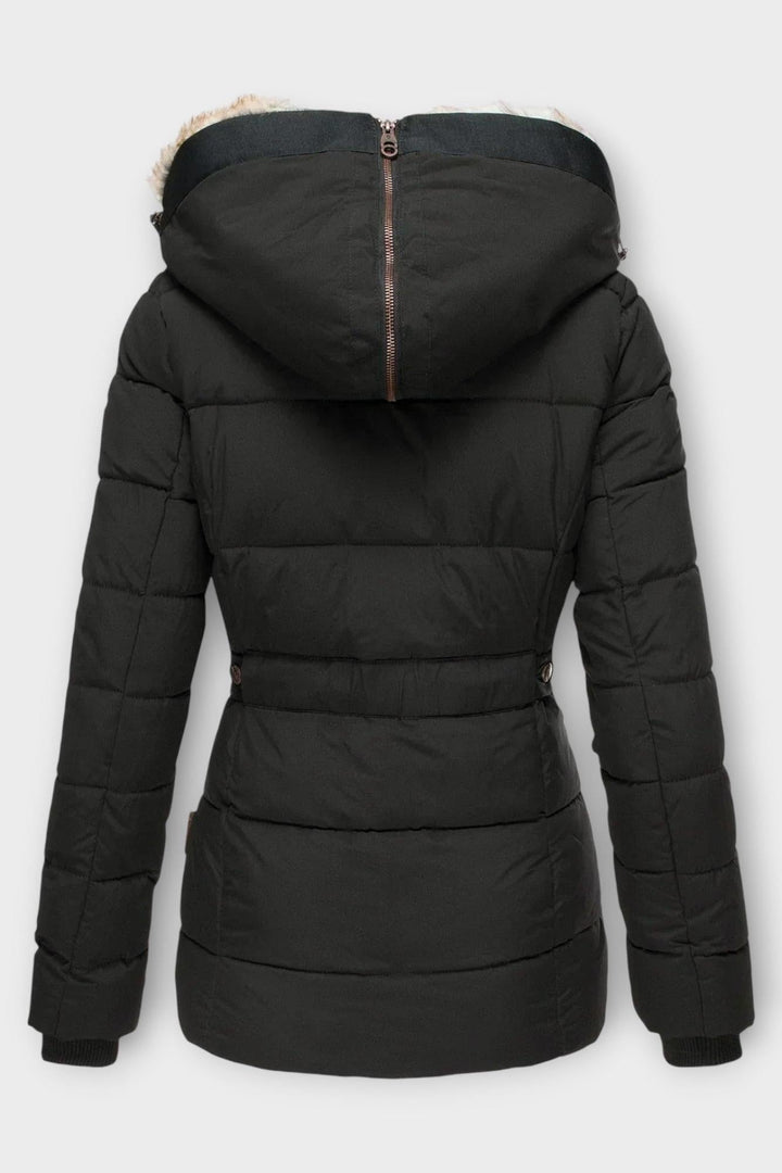 Model iført stilfuld kvindevinterfrakke med pelsfor, fremviser elegant dame mode.