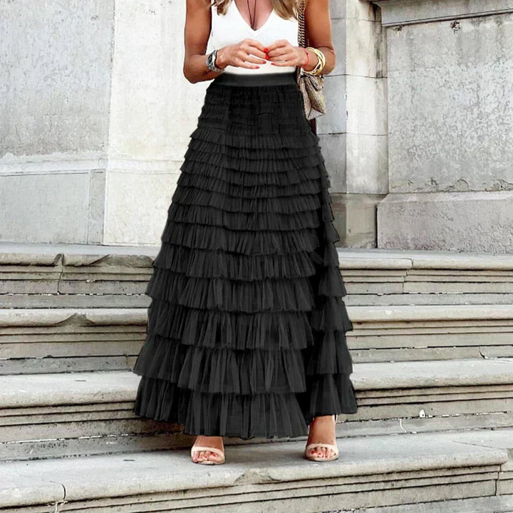 Kvinde bærer elegant maxinederdel m. lagdelte flæser. Lang flæsenenederdel i romantisk stil, perfekt til sommermode.