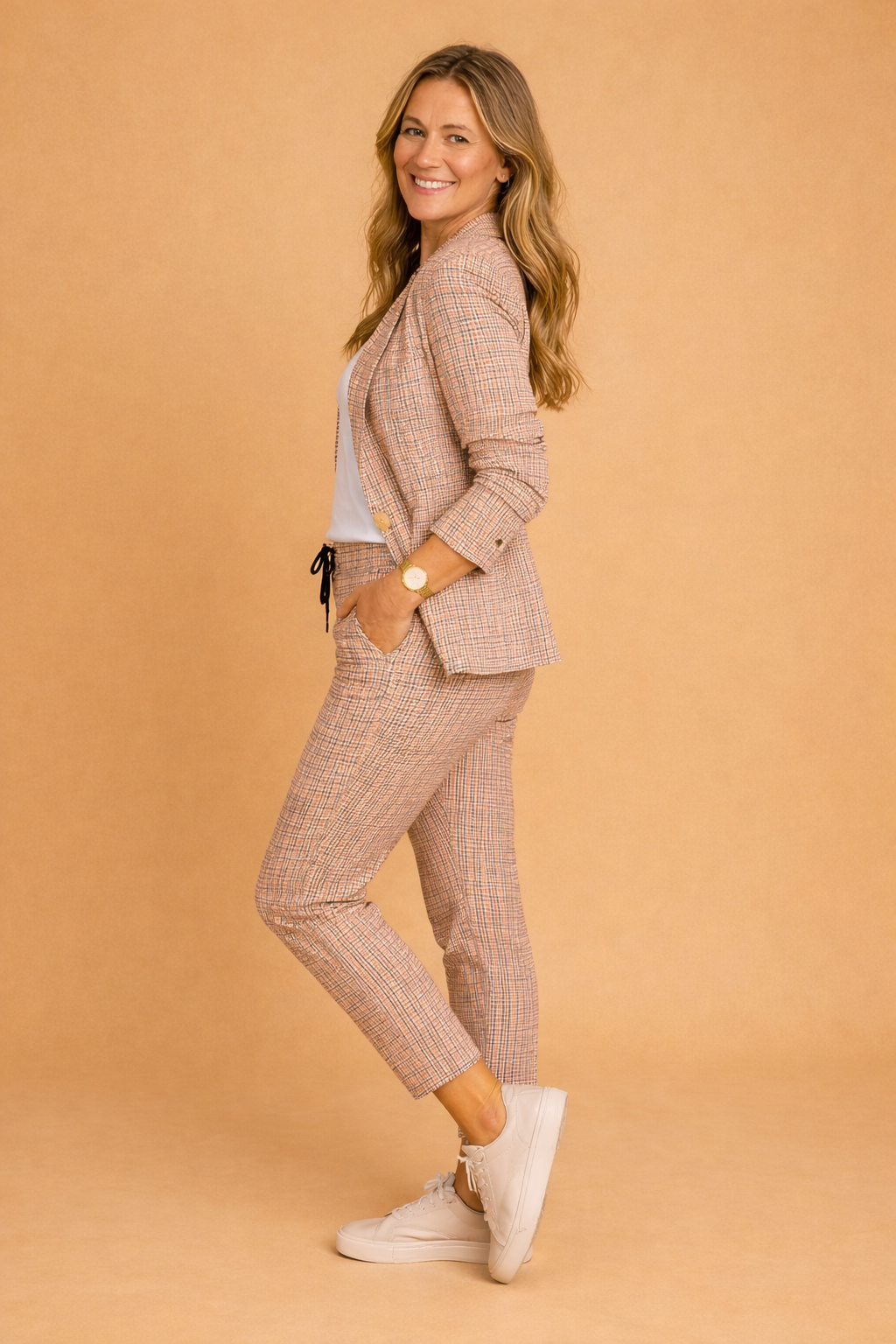 Lyserødt og gråt ternet todelt dame sæt med elegant smart-casual jakke og bukser. Moderne mode til kontoret eller fritid.