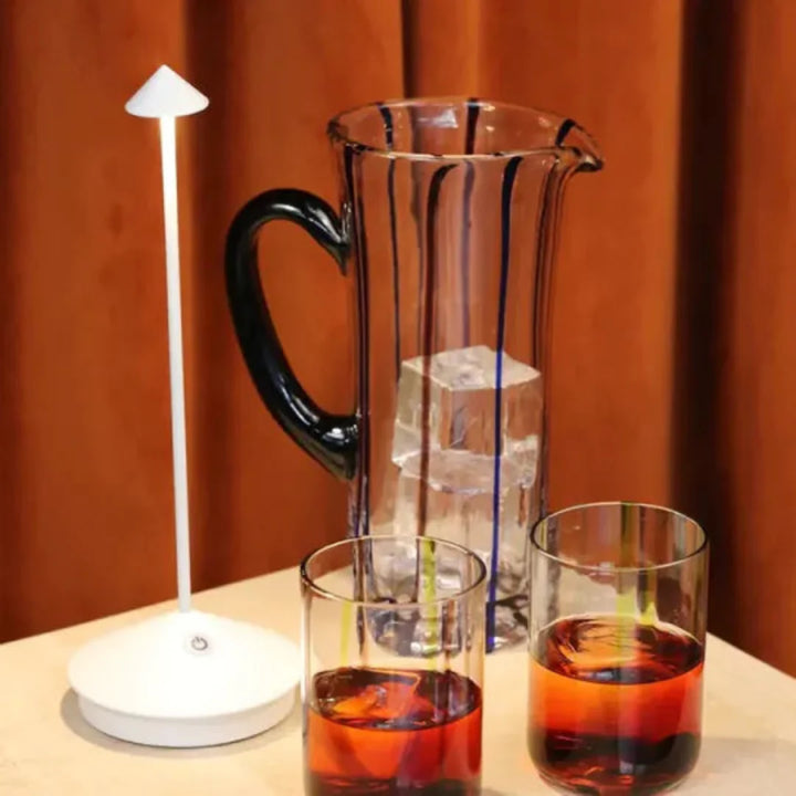 Bordlampe på et sidebord med bøger og en kop kaffe. Perfekt til afslapning og læsning.