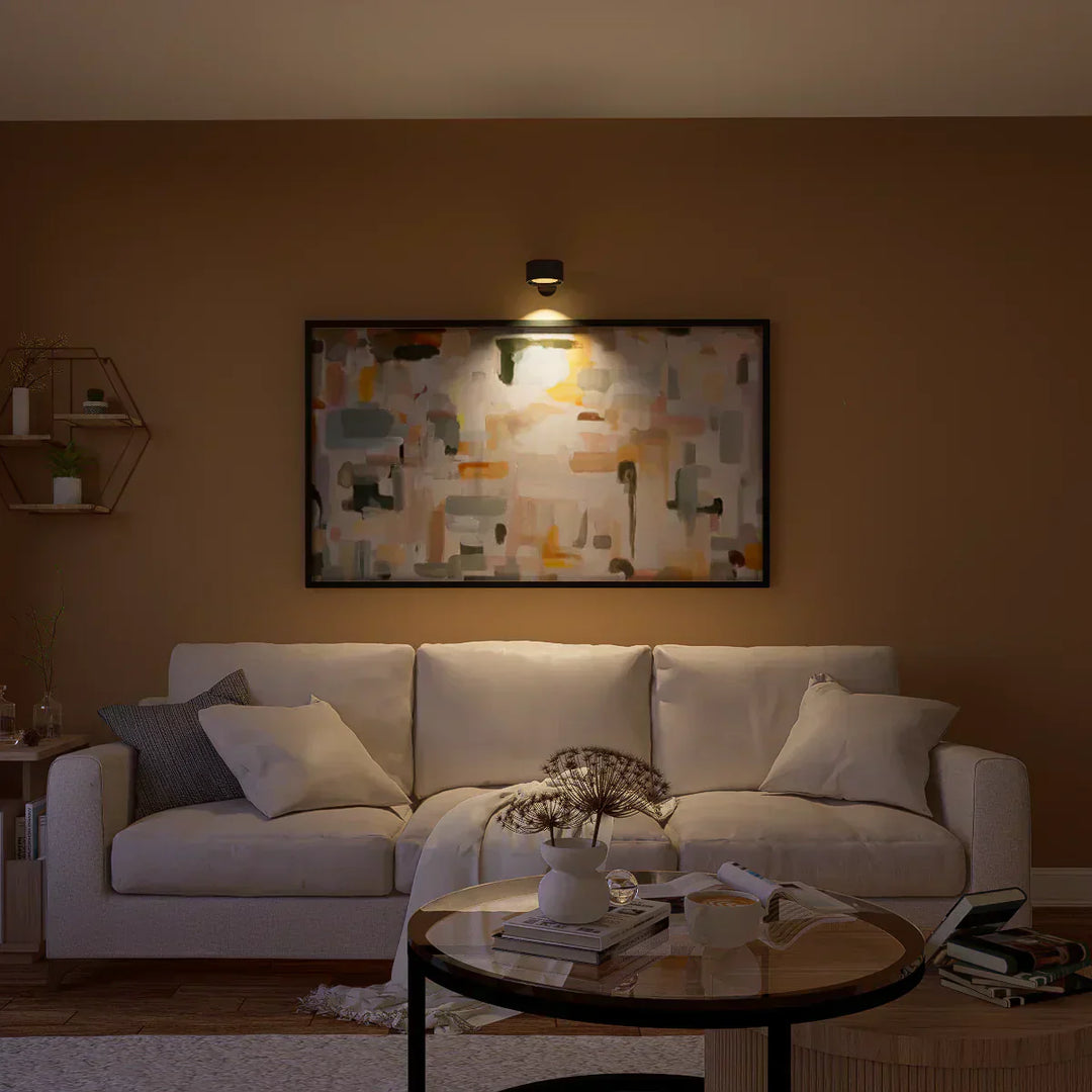 Elegant trådløs væglampe i sort set fra siden, med dæmpbart LED-lys og 360° drejelig funktion for fleksibel positionering.