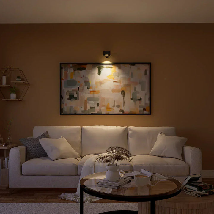 Elegant trådløs væglampe i sort set fra siden, med dæmpbart LED-lys og 360° drejelig funktion for fleksibel positionering.