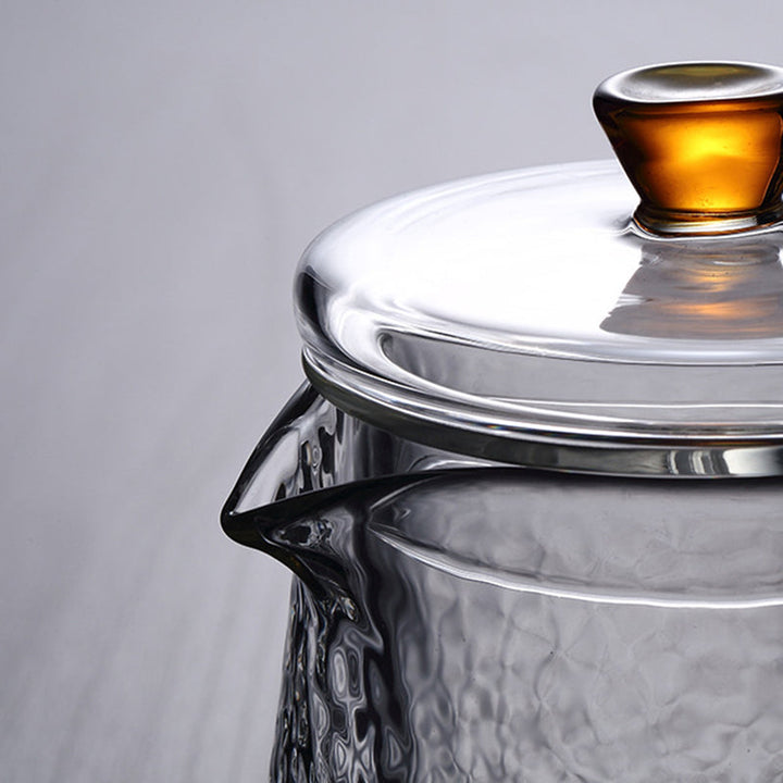 Elegant tekande af hamret, varmebestandigt glas med indbygget si og guldfarvet håndtag. Perfekt til teenydelse.