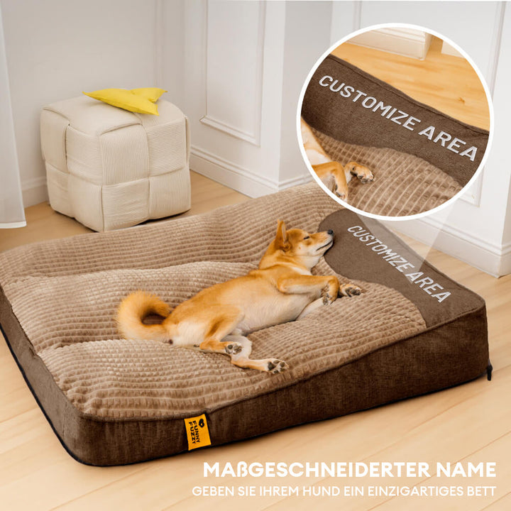 En hund sover komfortabelt på en stor, ridsefast pudehundeseng, der tilbyder ortopædisk støtte og tyk polstring.