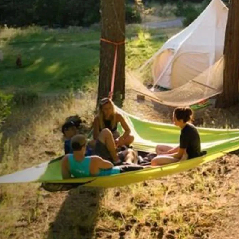 Rummelig grøn flerpersoners hængekøje i skoven til camping og familieeventyr, perfekt til naturoplevelser.