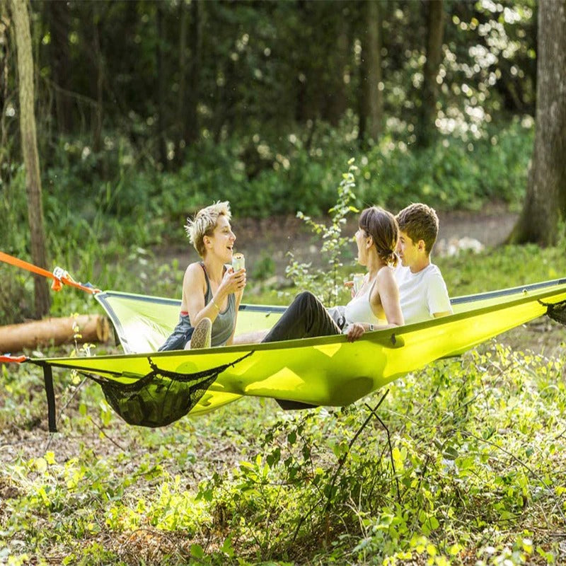 Rummelig grøn flerpersoners hængekøje i skoven til camping og familieeventyr, perfekt til naturoplevelser.