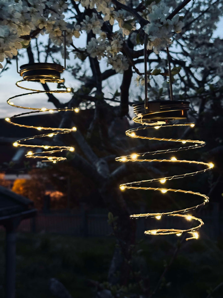 Gylden solcelle spiral lampe i metal, perfekt til udendørs havebelysning. Skaber hyggelig stemning med LED lys.