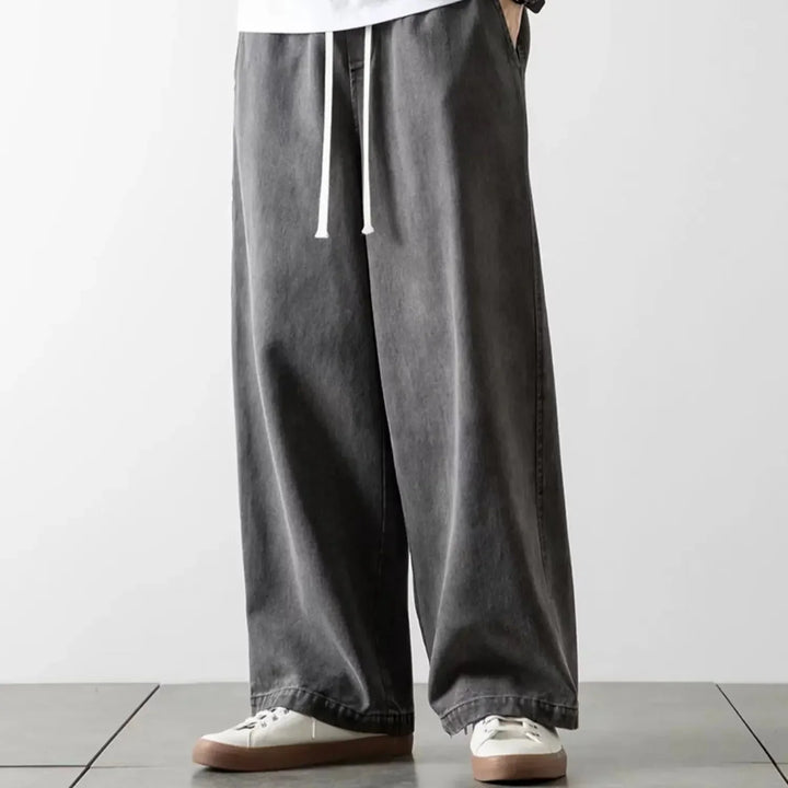 Mand bærer blå baggy jeans med afslappet pasform. Perfekt til streetwear og hverdag med elastisk talje.