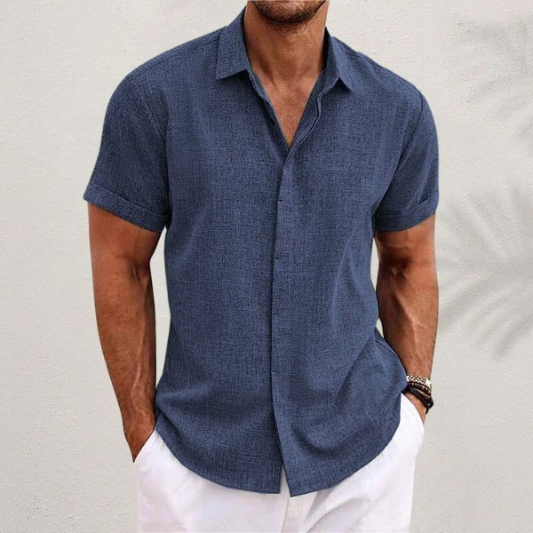 Moderne herre poserer i en kortærmet, afslappet sommerskjorte. Perfekt casual sommerlook.