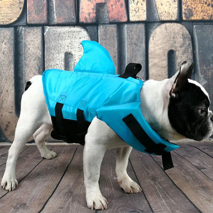 Hundesvømmevest med hajfinne i blåt stof, justerbare stropper for optimal sikkerhed i vandet, egnet til hunde i alle størrelser.
