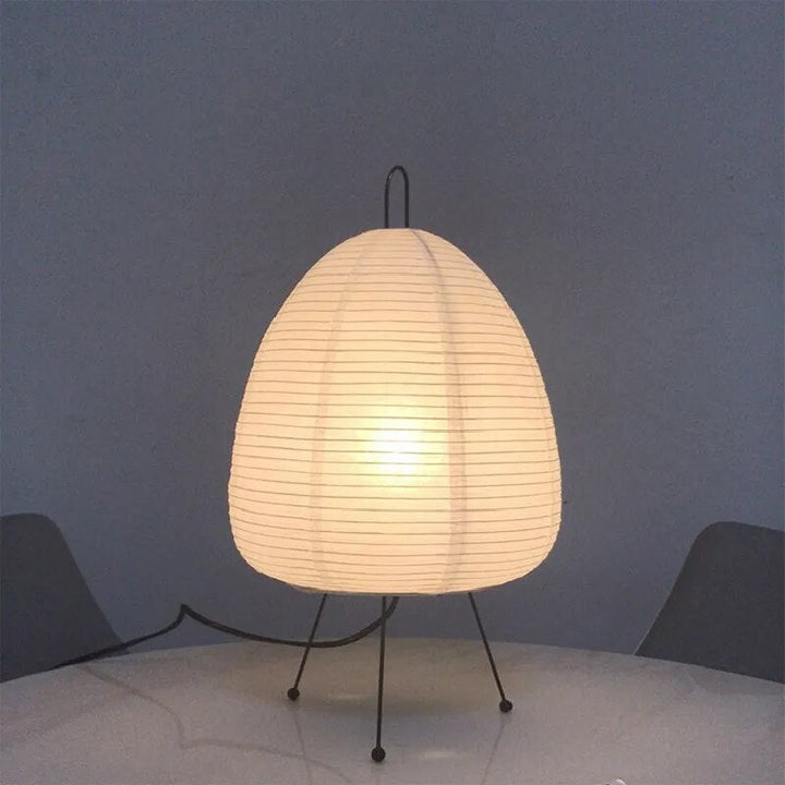Japansk bordlampe af rispapir, udsender varmt, diffust lys, elegant og tidløst design til indretning.