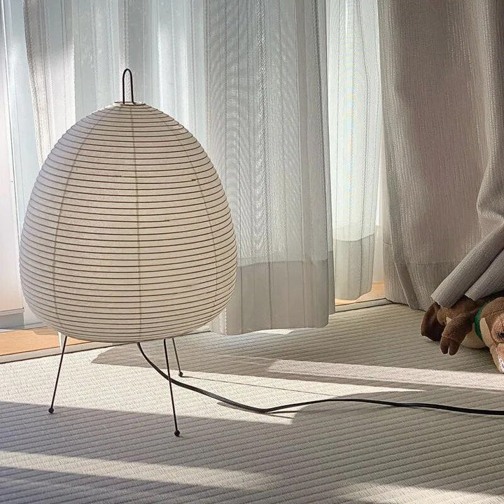 Japansk bordlampe af rispapir, udsender varmt, diffust lys, elegant og tidløst design til indretning.