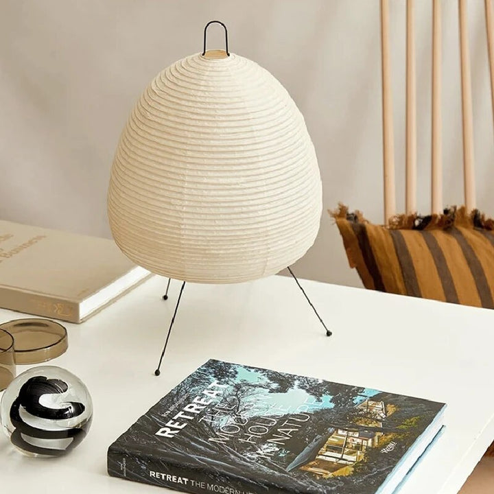 Japansk bordlampe af rispapir, udsender varmt, diffust lys, elegant og tidløst design til indretning.