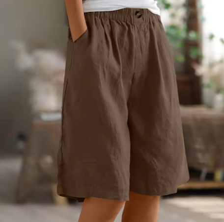 En kvinde sidder afslappet i løse shorts, perfekt til en komfortabel hverdag og sommerstil.