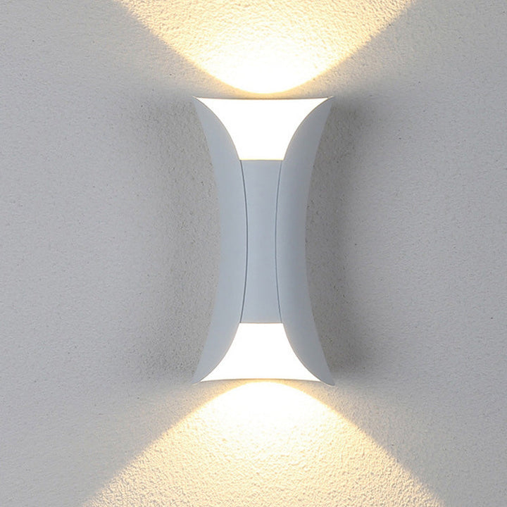 Detalje af moderne sort og guld LED væglampe, fremhæver designet for udendørs havebelysning.