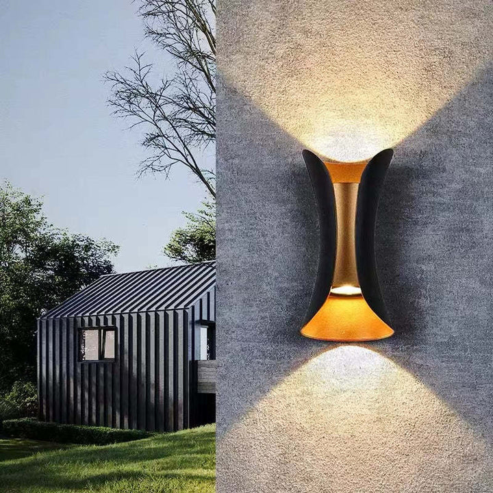 Moderne LED væglampe monteret på mur, giver varmt lys til udendørs terrasseområde.