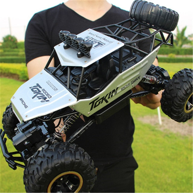 Blå fjernstyret 4WD monster truck i fuld fart, springer over en sten på en gruset offroad bane.