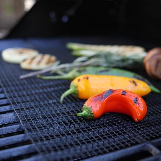 Effektiv rengøring af sort non-stick grillmåtte efter brug, klar til næste grillaften.