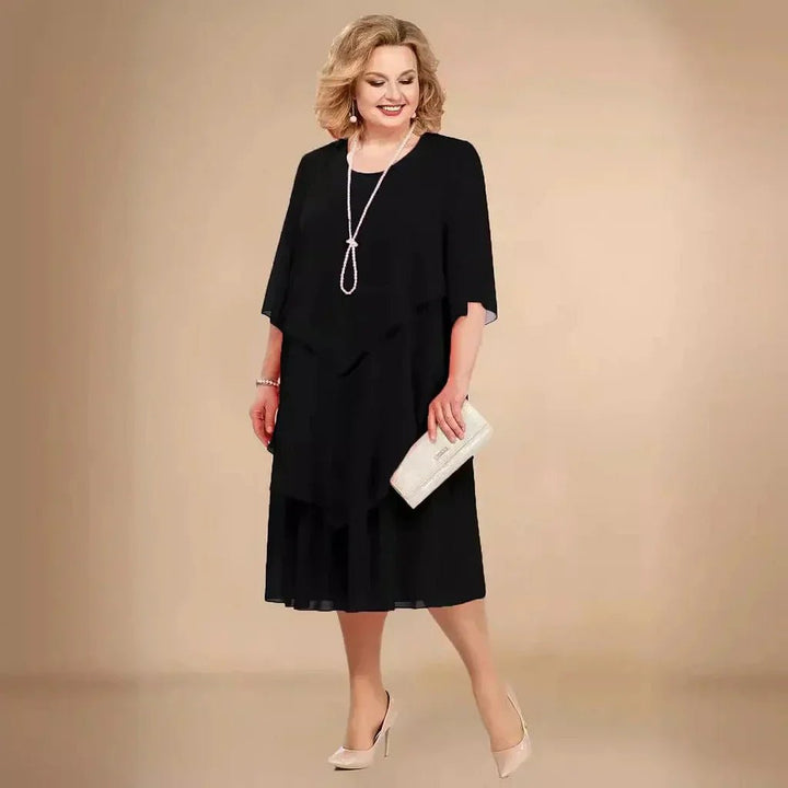 Sort elegant plus size chiffon kjole med asymmetriske lag. Perfekt som festkjole eller aftenkjole i store størrelser.