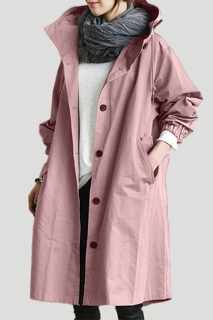 Kvinde iført stilfuld vandtæt regn trenchcoat med hætte. Mode overtøj til en tør hverdag.