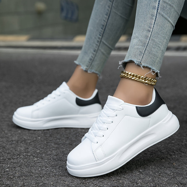 Sidebillede af moderne hvide dame sneakers med stilfulde sorte accenter, ideelle til casual brug.