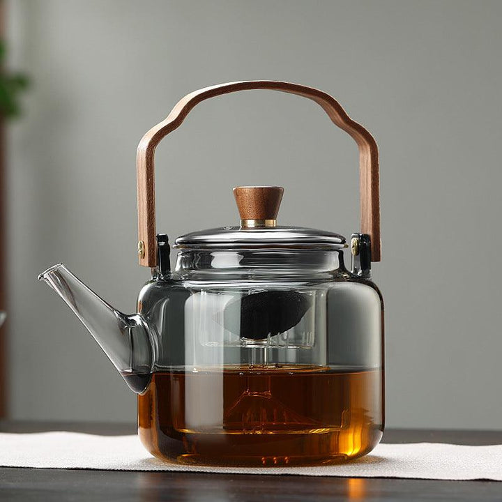 Stilfuld tekande i glas og træ med elegant design og ergonomisk greb, ideel til teceremonier.
