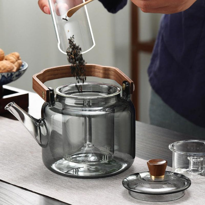 Stilfuld tekande i glas og træ med elegant design og ergonomisk greb, ideel til teceremonier.