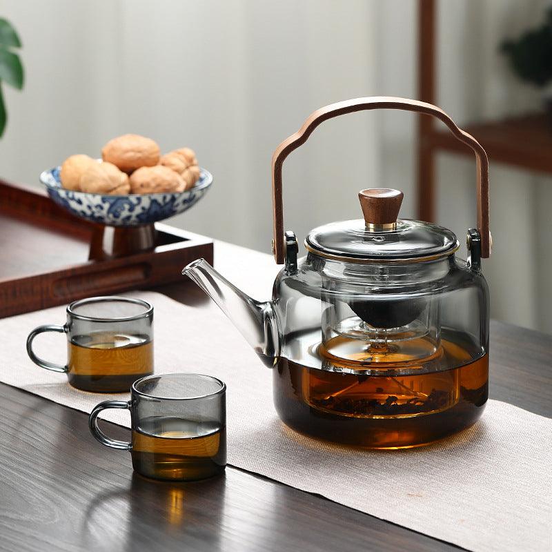 Stilfuld tekande i glas og træ med elegant design og ergonomisk greb, ideel til teceremonier.
