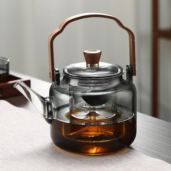 Stilfuld tekande i glas og træ med elegant design og ergonomisk greb, ideel til teceremonier.