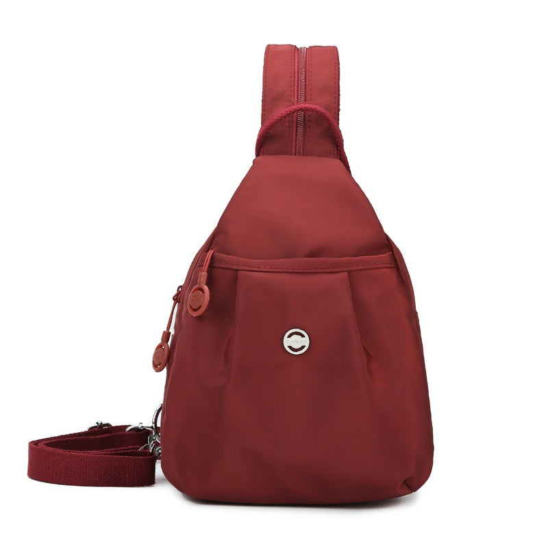 Person bærer den konvertible taske som en stilfuld crossbody i oxfordstof. Nem at omdanne til rygsæk.