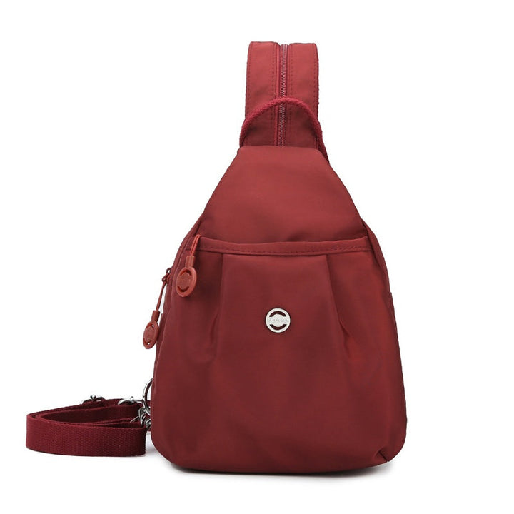Person bærer den konvertible taske som en stilfuld crossbody i oxfordstof. Nem at omdanne til rygsæk.